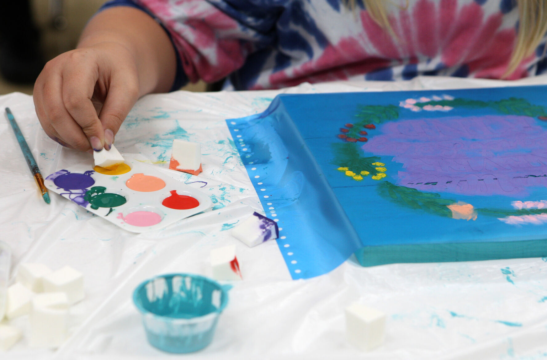 Lilly Raaf dips a sponge into paint